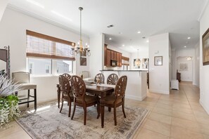A dining area with a wooden table and chairs, a chandelier, and a view of the outside. - Cinnamon Beach 5th floor ocean condo 155 - incredible views! (Palm Coast)