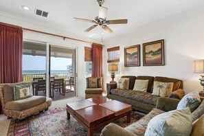 Ein geräumiges Wohnzimmer mit Balkon und Meerblick, ausgestattet mit Sofas und einem Couchtisch.