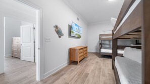 A room with a bunk bed, a wooden dresser, and a door leading to another room. - Unreal Views from this Beachfront 4BR Beauty! (Gulf Shores)