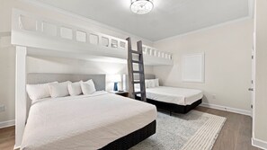 Ein Schlafzimmer mit zwei Betten, einer Leiter, einem Nachttisch und einem an der Wand befestigten Regal.