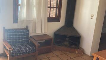 A living room with a sofa, a small table, a fireplace, and a window with curtains.