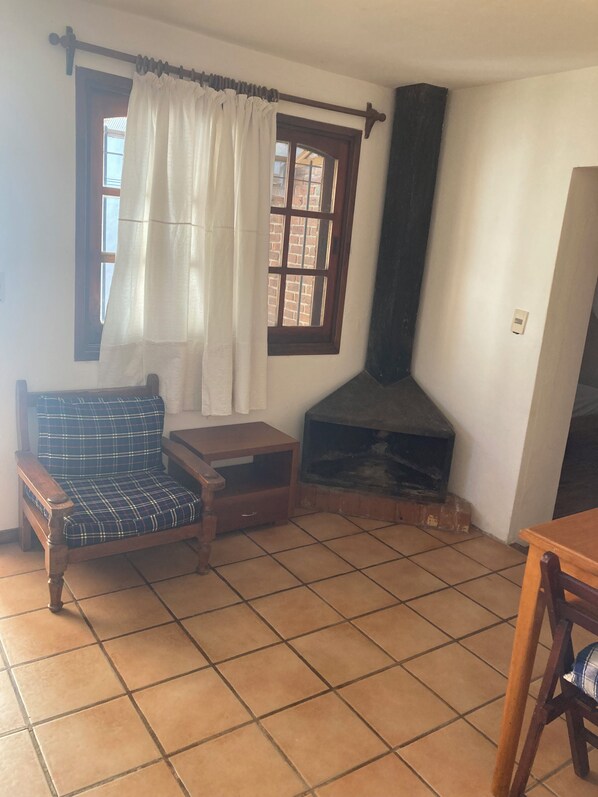 A living room with a sofa, a small table, a fireplace, and a window with curtains.