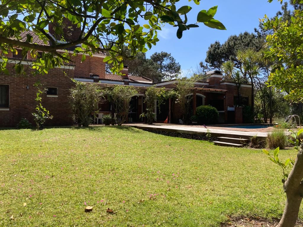 A residential property with a brick house, a swimming pool, and a well-maintained lawn.