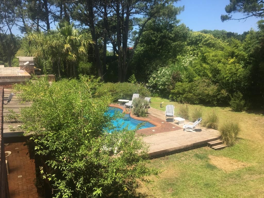 A backyard with a swimming pool, deck, and lounge chairs.