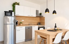 Een moderne keuken met roestvrijstalen apparatuur, een houten aanrecht en een eethoek met een tafel en stoelen.