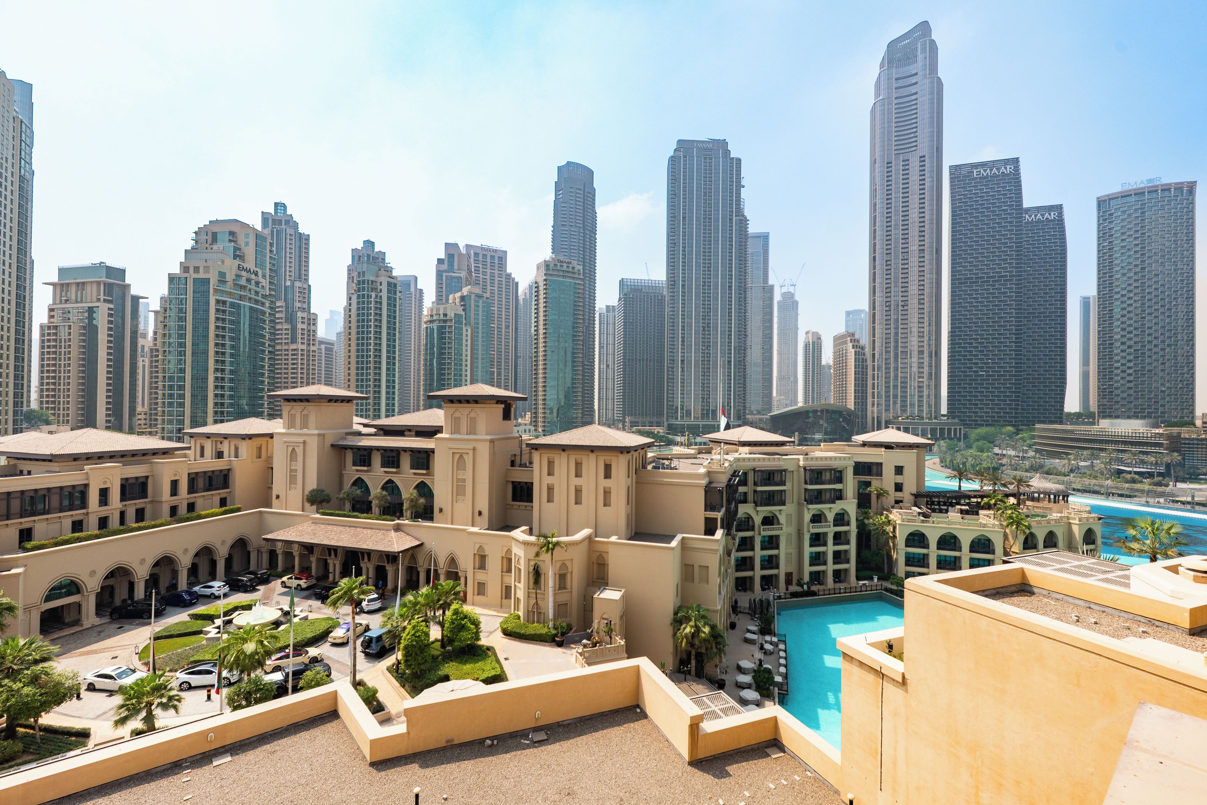 A modern hotel with a pool, surrounded by high-rise buildings.