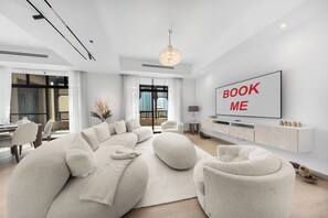 Uma sala de estar moderna com um sofá seccional grande, uma TV de tela plana na parede e um candelabro.