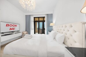 Quarto de hotel com cama grande, televisão, escrivaninha e vista para a cidade.