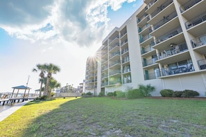 A multi-story hotel with balconies, a grassy area in front, and a view of the sea. - Wind Drift North 311 by Liquid Life (Orange Beach)