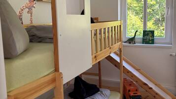 A child's bunk bed with a window view, a toy train, and a giraffe decoration.
