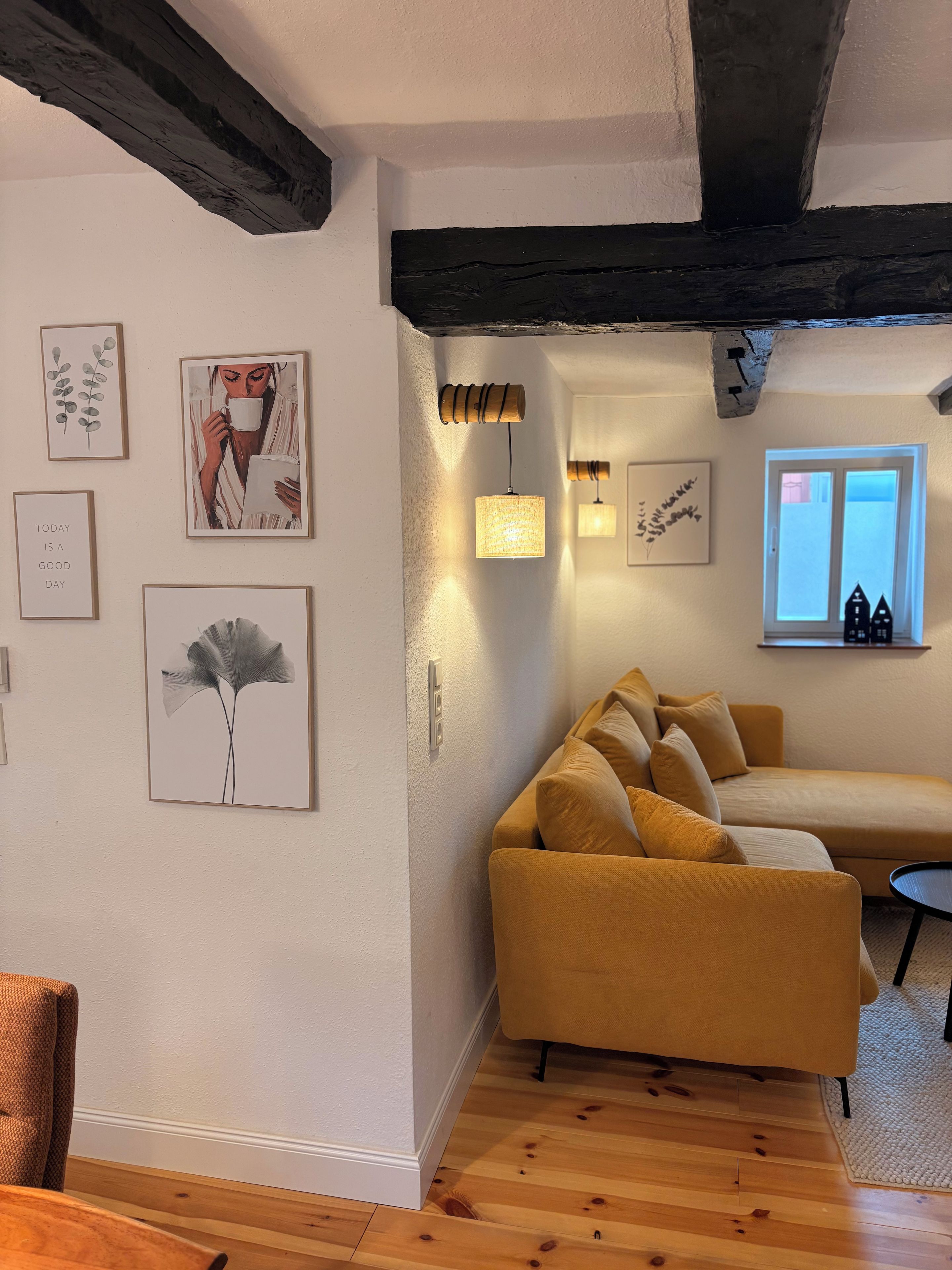 Ein gemütliches Wohnzimmer mit einer Couch, gerahmten Bildern und einem Fenster mit Ausblick.