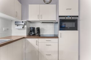 A modern kitchen with white cabinets, a coffee maker, a Siemens oven, and a clock on the wall. - Blankenberge Stay Near Market (Blankenberge)