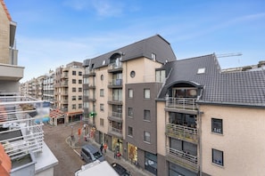 Ein mehrstöckiges Wohngebäude mit Balkonen, einem sichtbaren Laden und blauem Himmel.