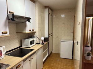 Eine kleine Küche mit Mikrowelle, Toaster, Wasserkocher und einem kleinen Kühlschrank.