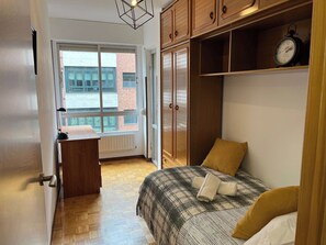 A bedroom with a bed, a wardrobe, a radiator, and a window with a view of buildings. - Oviedo 2BR Flat by HUCA Hospital · Sleeps 3 (Oviedo)