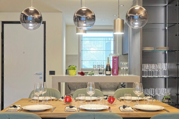 Un comedor con una mesa de madera dispuesta para seis personas, rodeada de sillas verdes.
