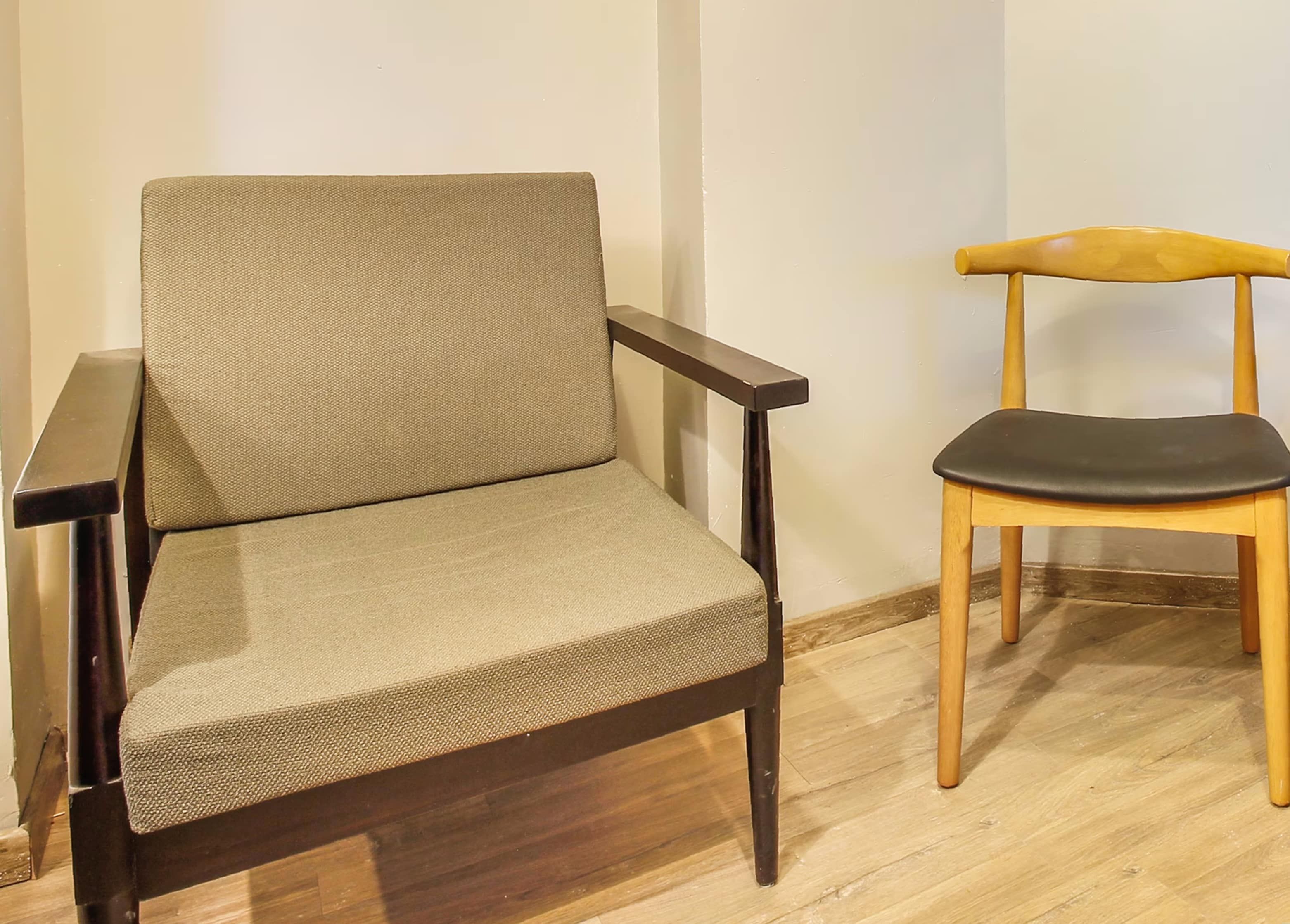 Una silla con estructura oscura y un cojín, ubicada junto a otra silla de madera con asiento claro.