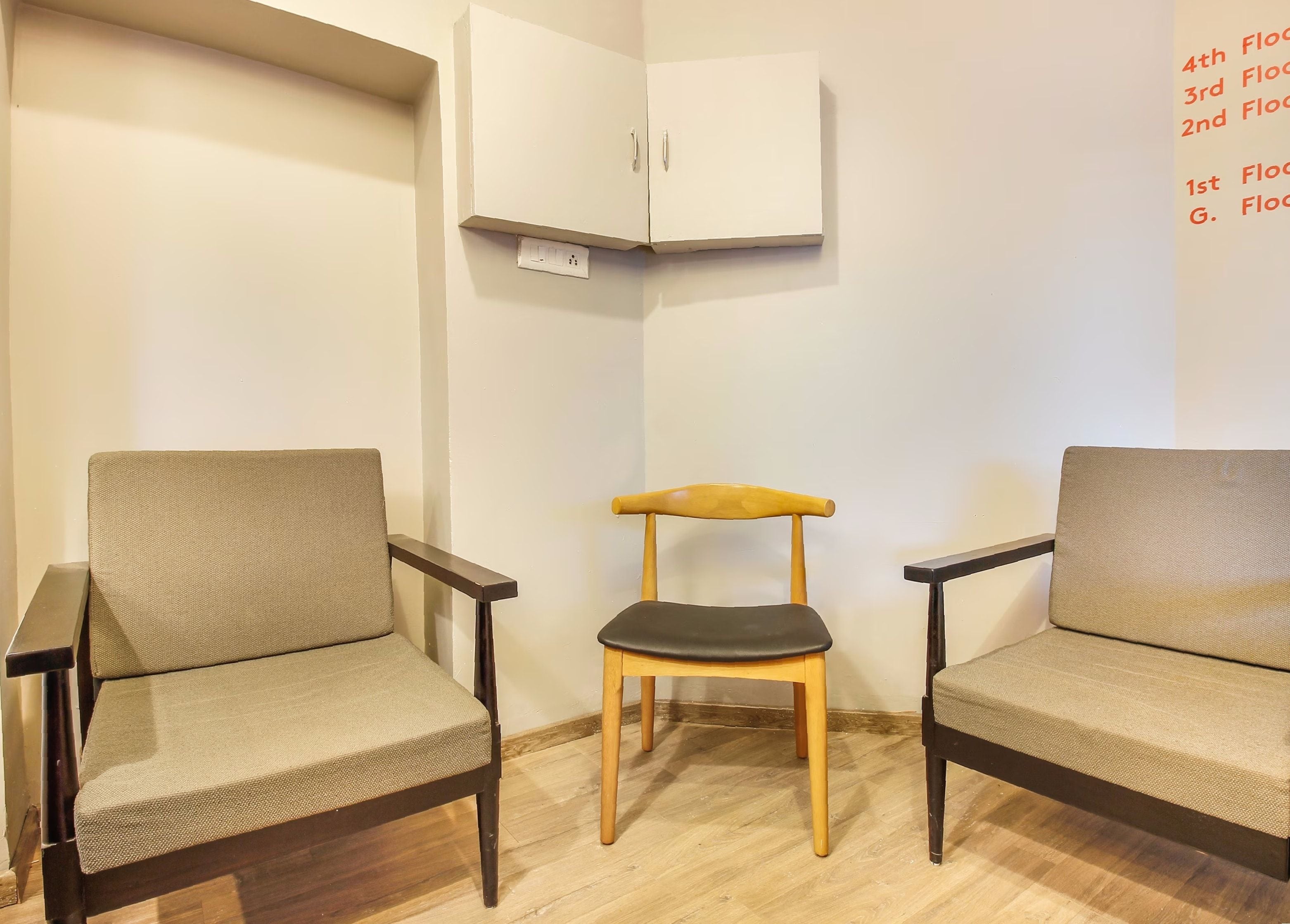 Een kamer met twee stoelen, een tafeltje en een kast.
