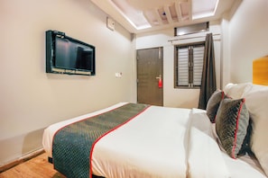 A hotel room with a bed, a television mounted on the wall, a window with curtains, and a door. - Super Townhouse RCC Sunrise (Hyderabad)