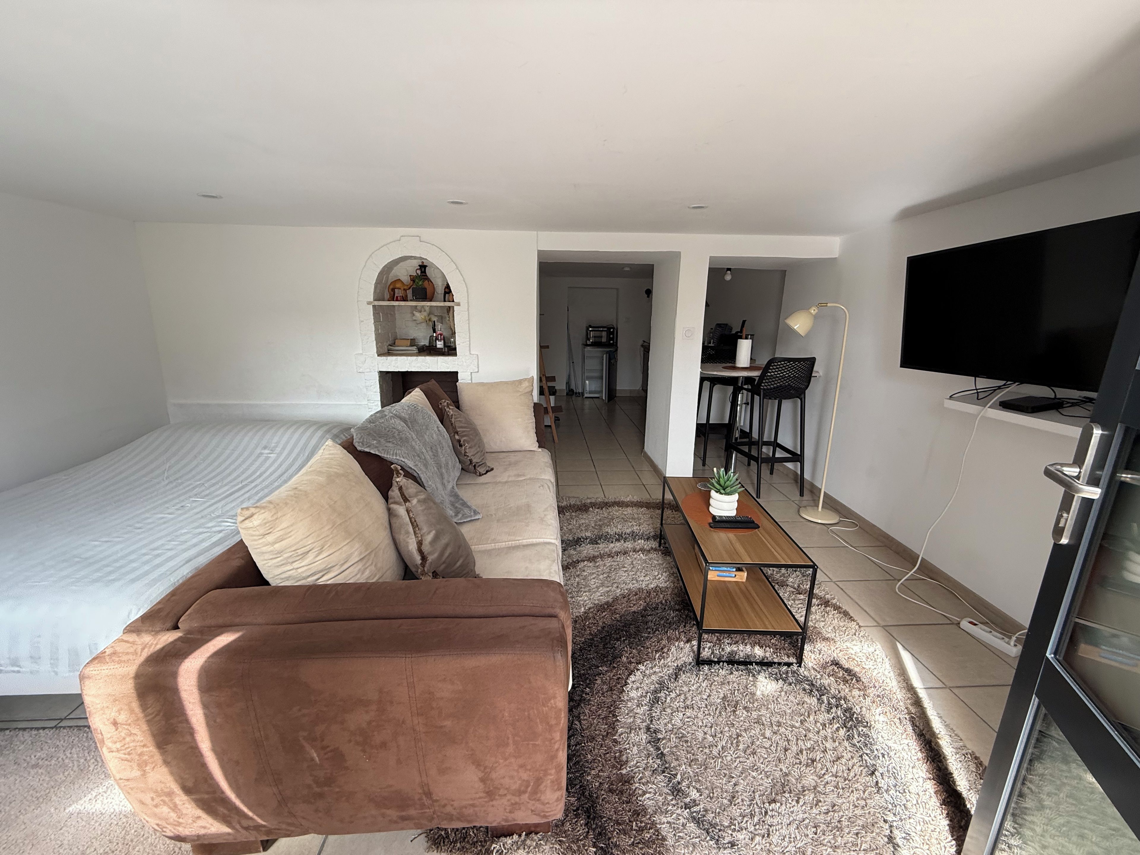 A modern living room with a sofa, a coffee table, a TV, and a fireplace.