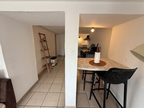 Cocina pequeña con comedor, una escalera y un cubo de basura.