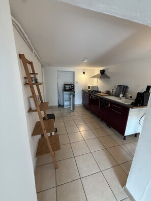 Una cocina con una escalera de madera, un microondas, una estufa y alacenas.