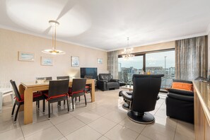Ein modernes Wohnzimmer mit Essbereich, großen Fenstern und Blick auf die Stadt.