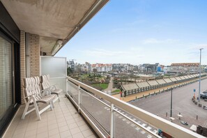 A balcony with a view of a cityscape, including a tram line and buildings. - 2-bedroom Home With Sun Terrace (Blankenberge)