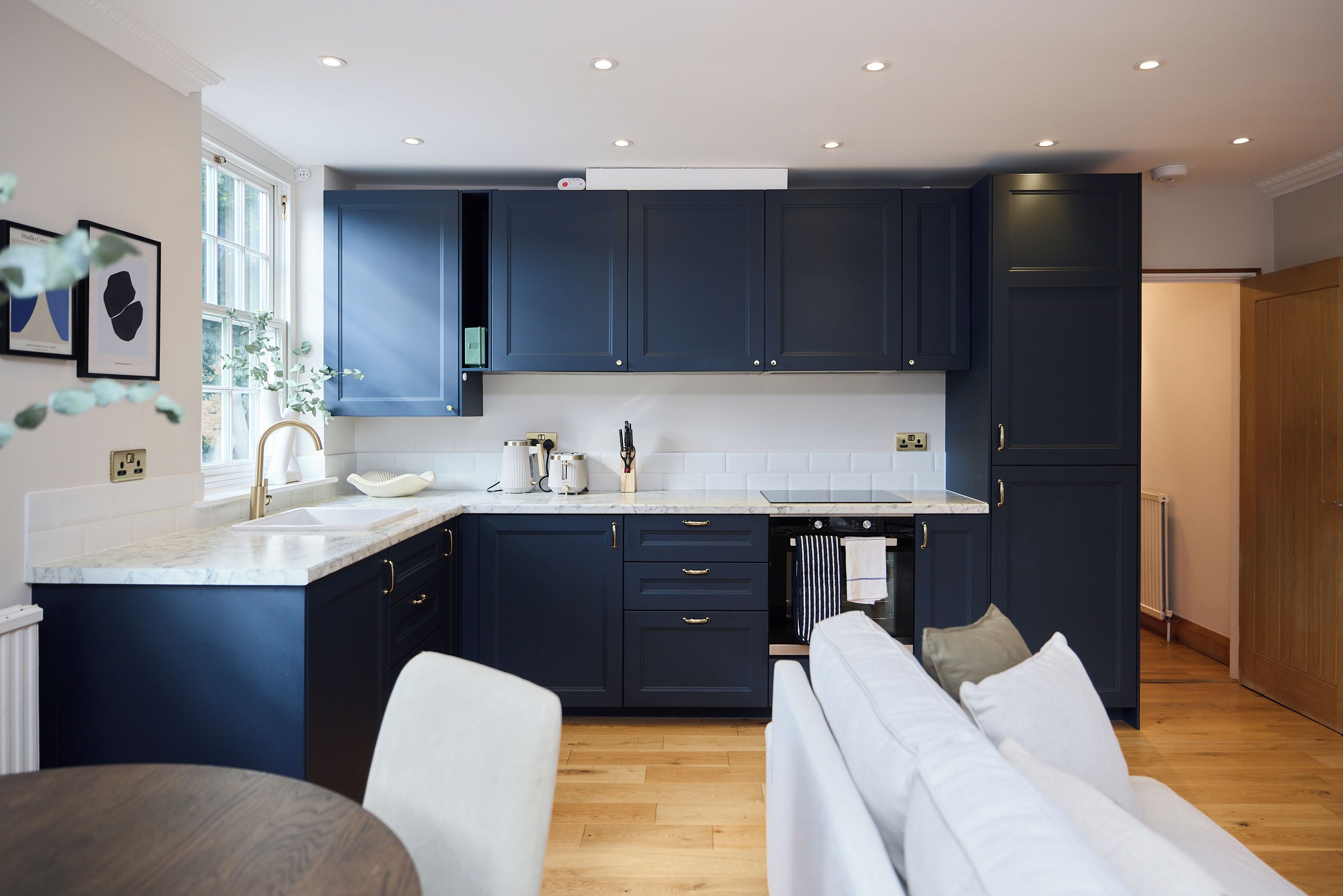 A modern kitchen with dark cabinets, a marble countertop, and a built-in oven.