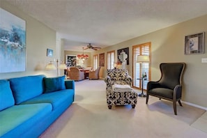 A living room with a blue sofa, patterned armchair, and a dark armchair. - Bring your boat and enjoy Southwest Florida from your own backyard. Royal Palm features a private dock and boat lift available for guest use, with canal access leading toward Charlotte Harbor and the Gulf of Mexico. (Port Charlotte)