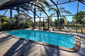 Ein Swimmingpool mit Blick auf Palmen und ein Haus in der Ferne.