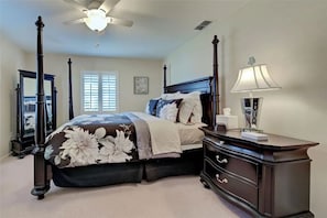 A bedroom with a four-poster bed, a ceiling fan, a bedside table with a lamp, and a dresser. - Bring your boat and enjoy Southwest Florida from your own backyard. Royal Palm features a private dock and boat lift available for guest use, with canal access leading toward Charlotte Harbor and the Gulf of Mexico. (Port Charlotte)