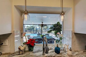 A kitchen with a view of a pool, a ceiling fan, and decorative items on the counter. - Bring your boat and enjoy Southwest Florida from your own backyard. Royal Palm features a private dock and boat lift available for guest use, with canal access leading toward Charlotte Harbor and the Gulf of Mexico. (Port Charlotte)