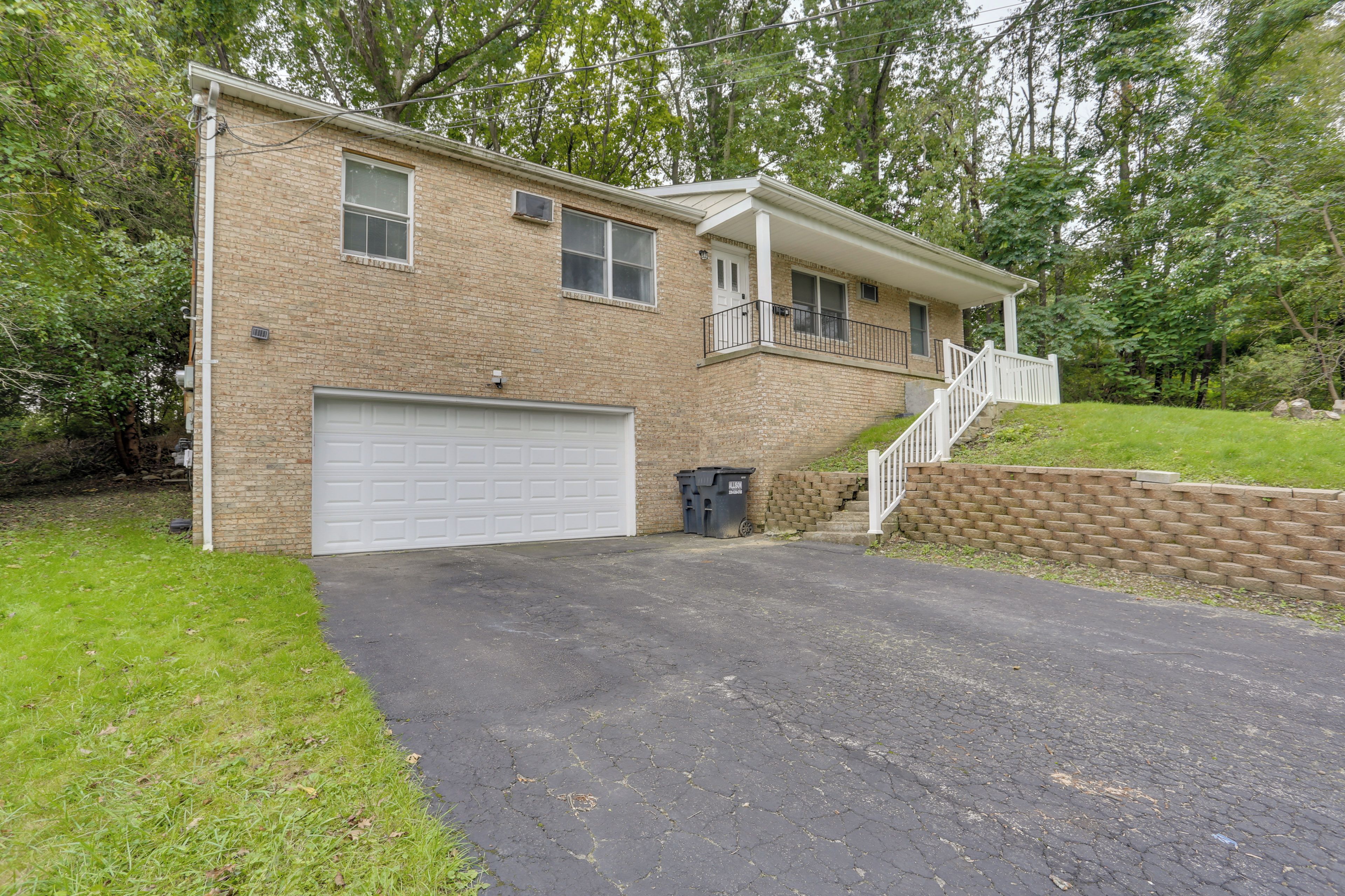 A two-story house with a garage, a front porch, and a brick exterior.