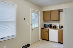 A compact kitchen with wooden cabinets, a microwave, a toaster, and a dishwasher. - Youngstown Home Near Fellows Gardens & Lake Milton (Youngstown)