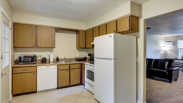 A kitchen with wooden cabinets, a white refrigerator, a microwave, and a dishwasher.