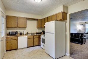 A kitchen with wooden cabinets, a white refrigerator, a microwave, and a dishwasher.