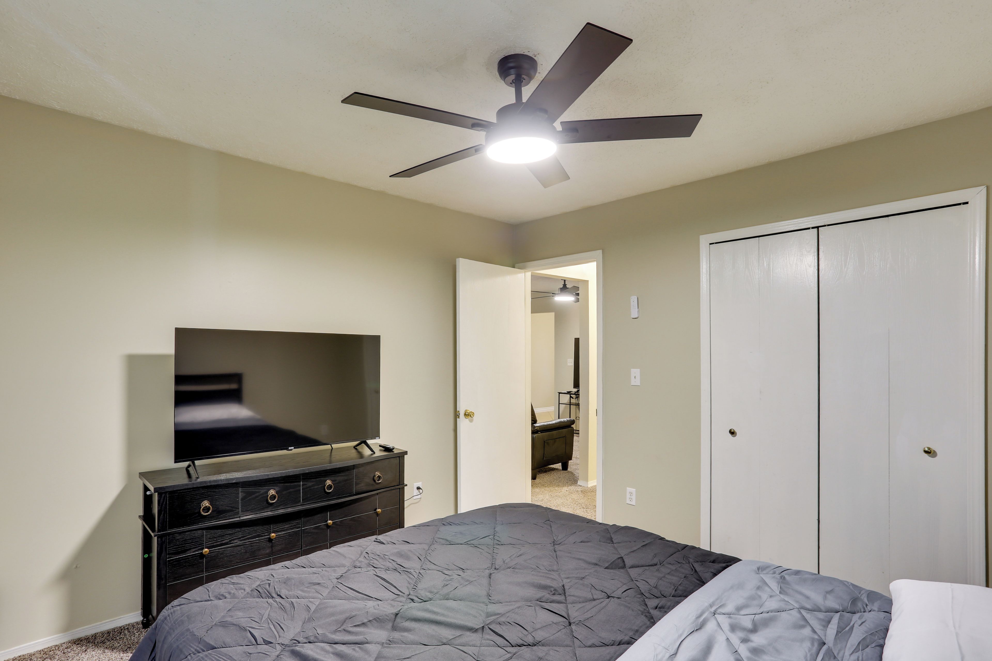 Un dormitorio con cama, cómoda, ventilador de techo y vestidor.