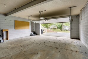 An open garage with a concrete floor, a pegboard on the wall, and a staircase leading outside. - Youngstown Home Near Fellows Gardens & Lake Milton (Youngstown)