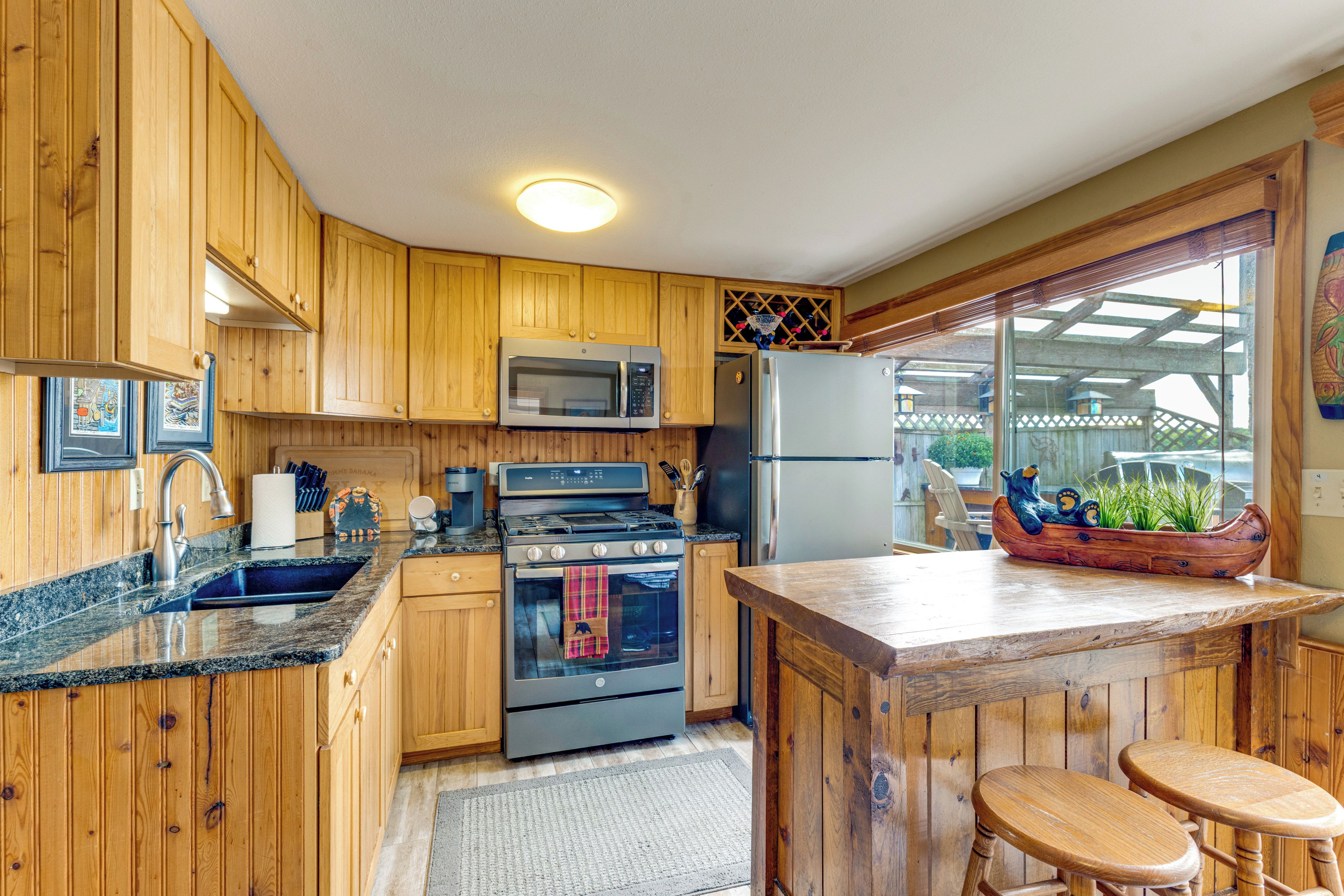 A kitchen with wooden cabinets, a stainless steel refrigerator, a microwave, and a stove.