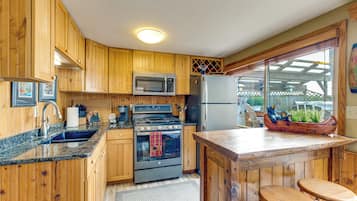 A kitchen with wooden cabinets, a stainless steel refrigerator, a microwave, and a stove.