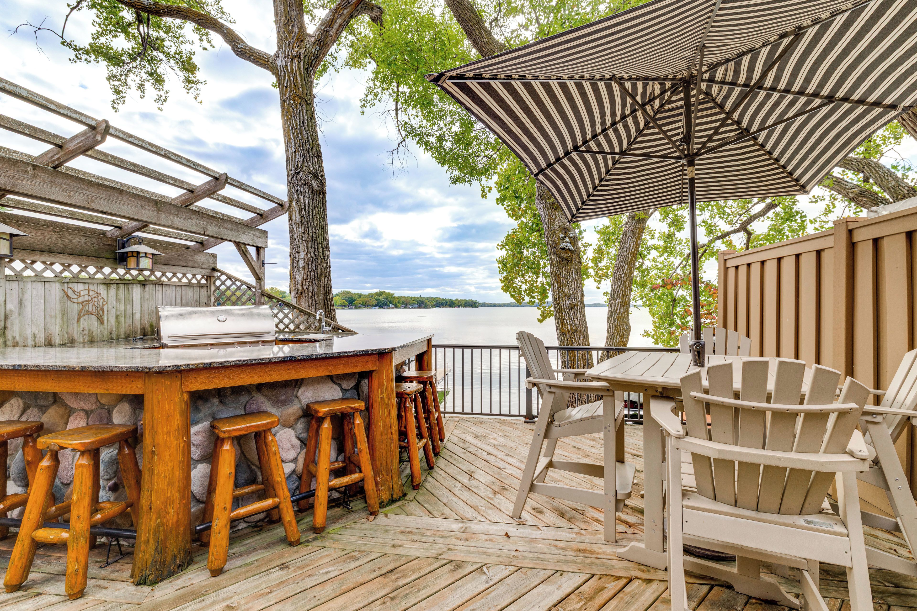 An outdoor deck with a bar area, seating, and a view of the water.