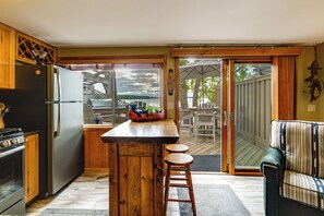 A kitchen with a wooden island, a refrigerator, and a view of the outdoors through a sliding glass door. - Tetonka Lake Views & Outdoor Entertainment Area! (Waterville)