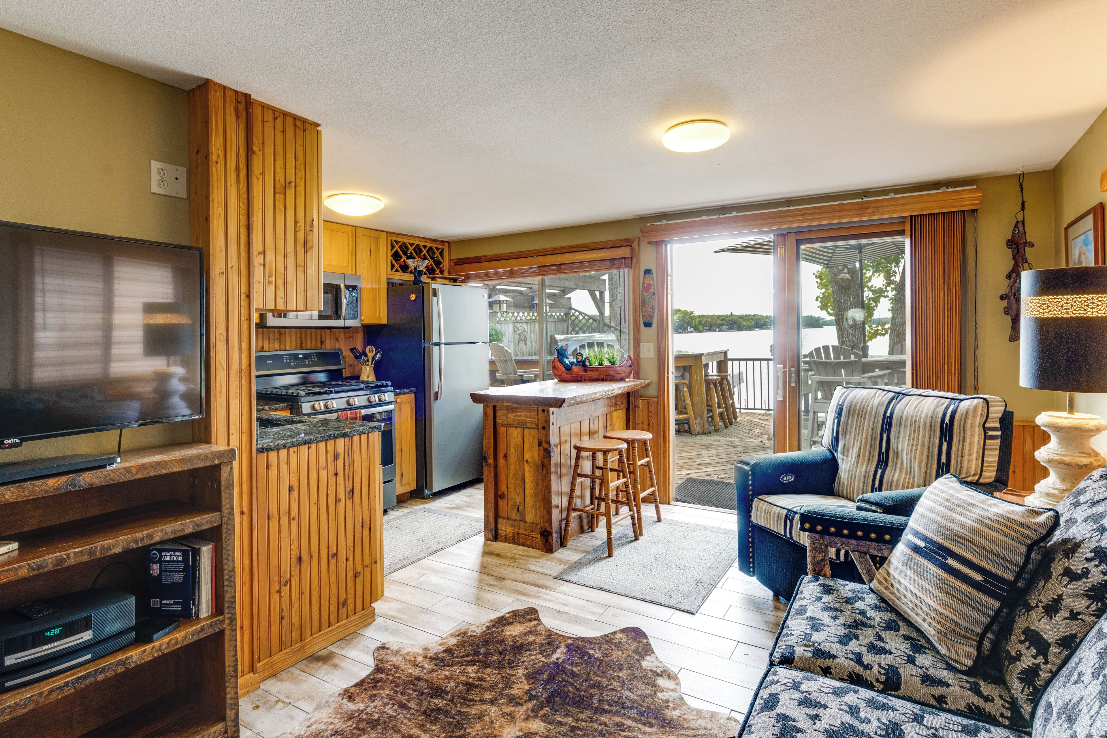 A compact living space with a kitchenette, a television, a sofa, and a view of the outdoors.