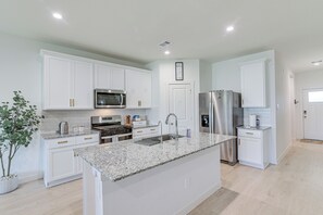 A modern kitchen with white cabinetry, stainless steel appliances, and a granite countertop. - Modern Fresno Home w/ Yard: Near Parks & Shopping (Fresno)
