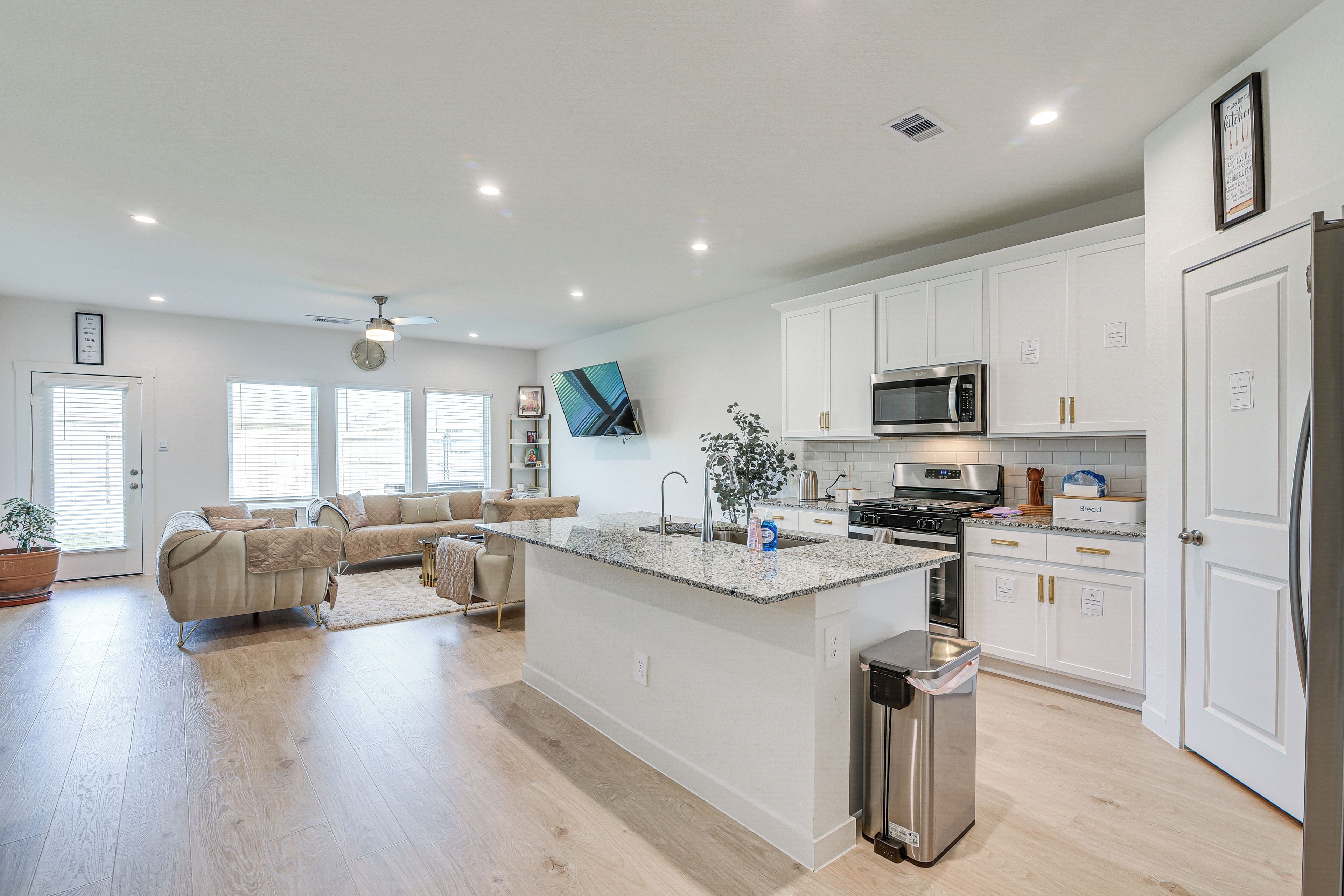 A modern kitchen with white cabinetry, a stainless steel refrigerator, a microwave, and a built-in oven.