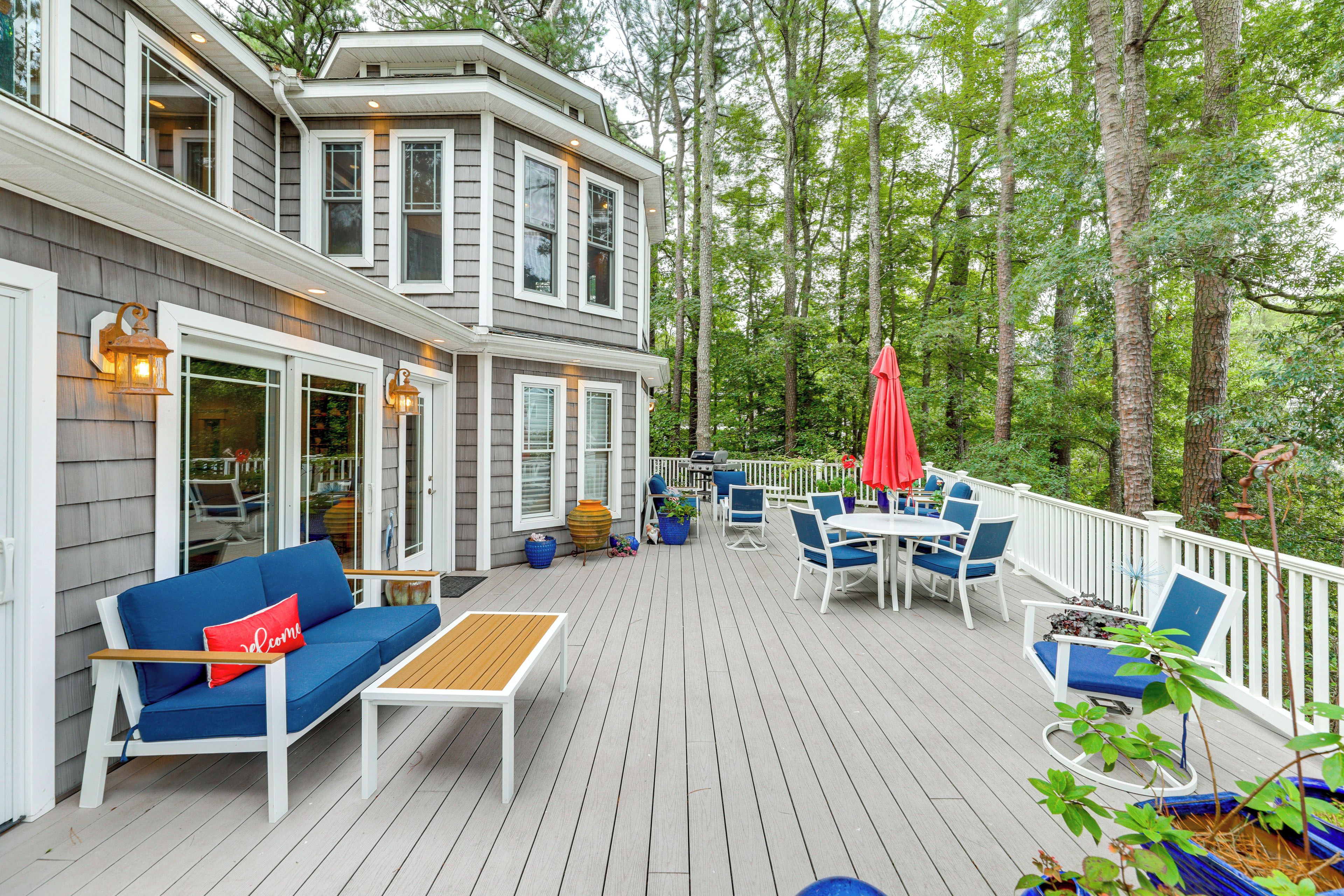 A deck with outdoor furniture, a barbecue grill, and a red umbrella.