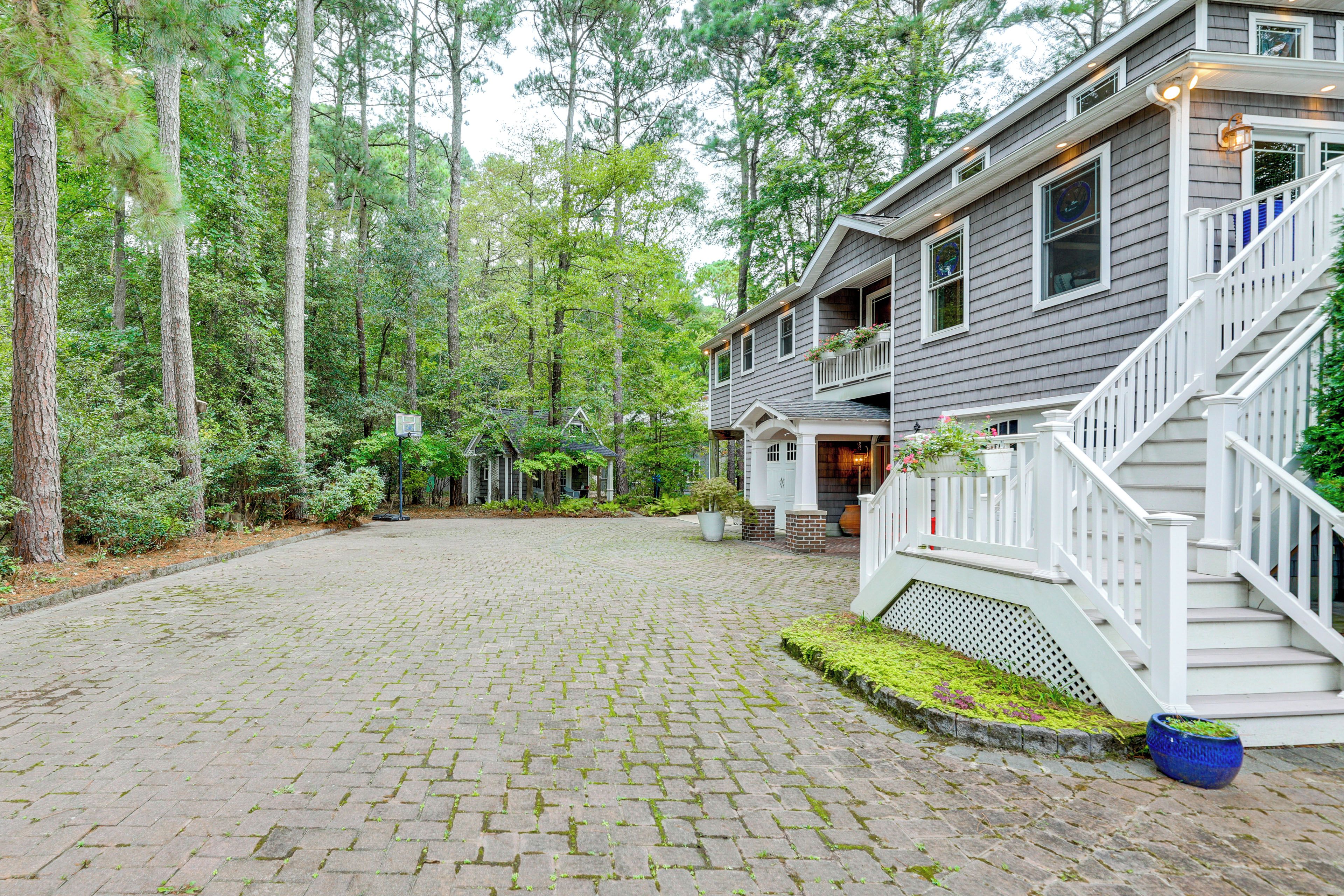 A two-story house with a paved driveway and a staircase leading to the entrance.