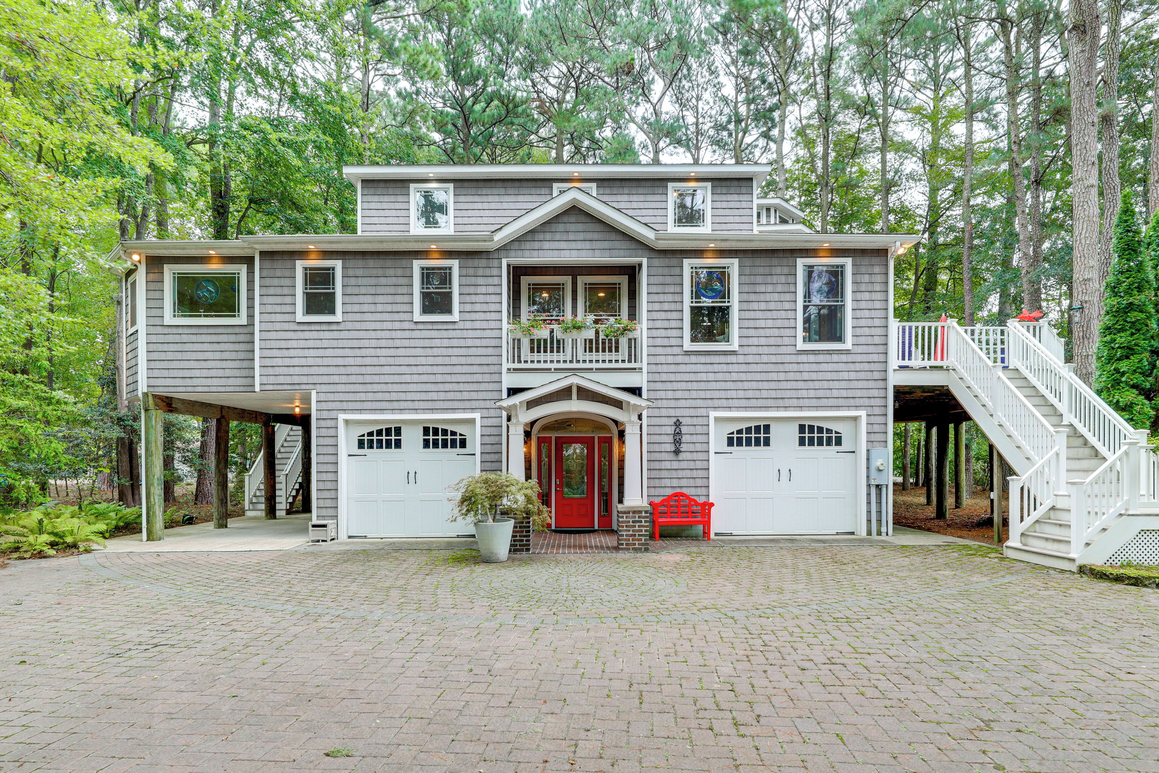A two-story house with a front porch, a red door, and a staircase leading to the upper level.