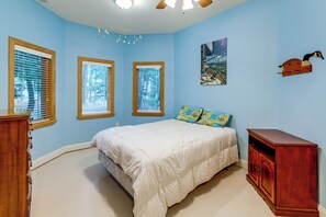 Un dormitorio con una cama, un armario de madera y tres ventanas con persianas.